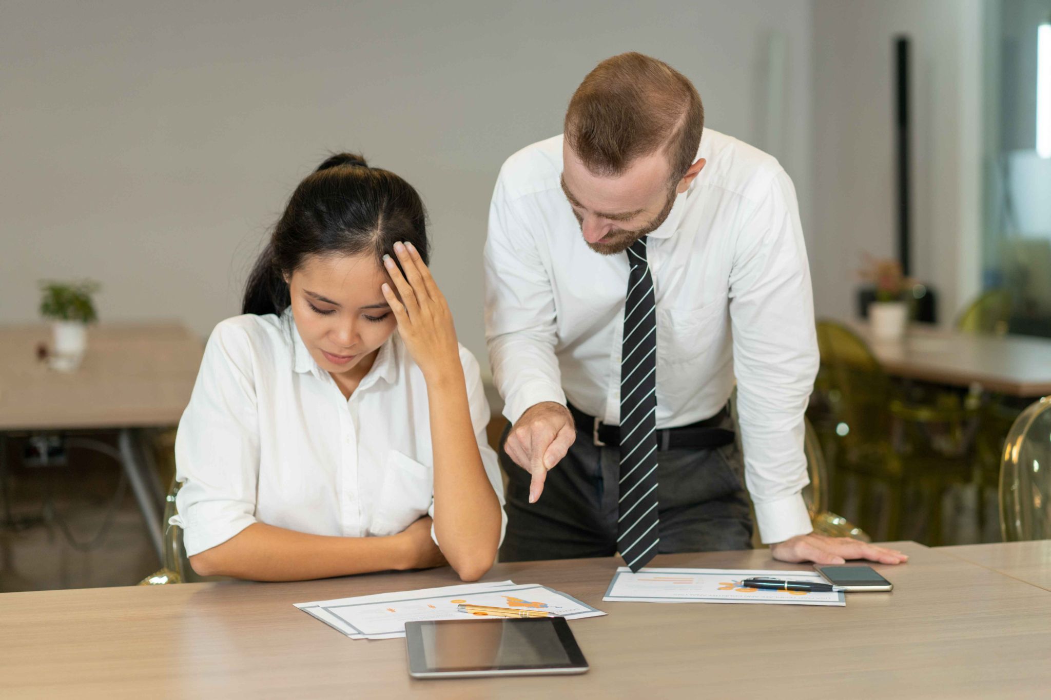 Manager pointing at tablet while employee looks stressed