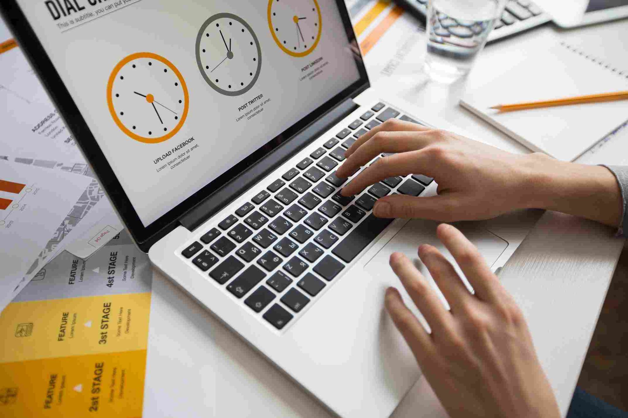Person typing on a laptop with clocks displayed on the screen