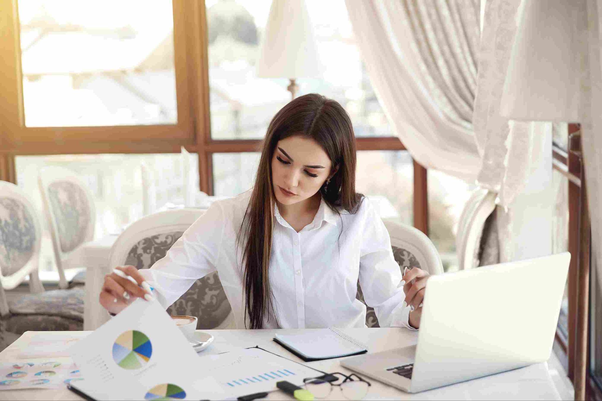 Woman working at a desk with laptop and charts