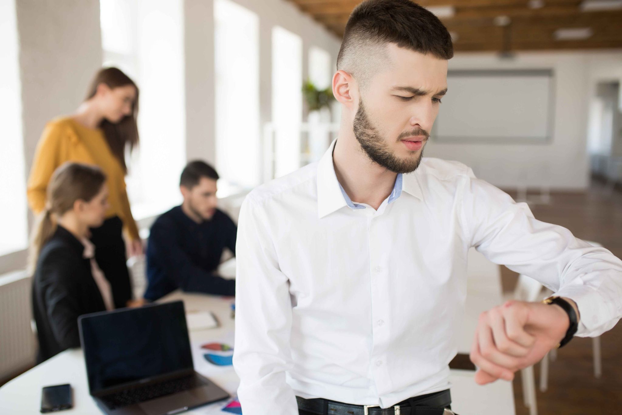 Employee checking time while team works in office