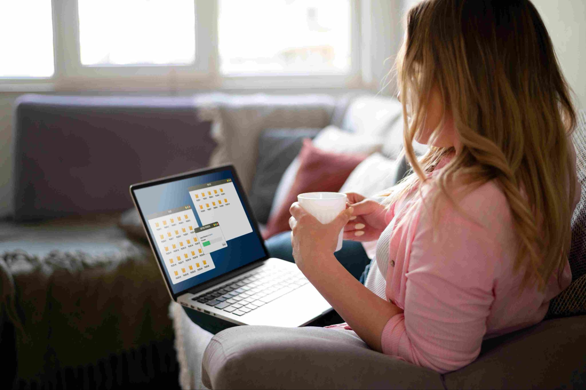 Woman sitting on a couch using a laptop showing a timesheet interface
