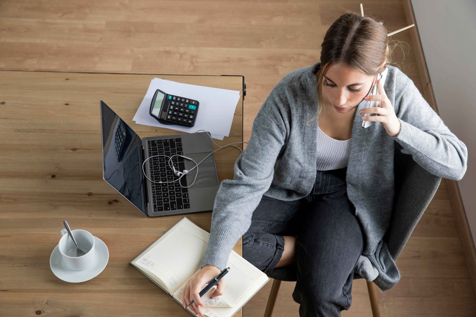 Woman sitting on the floor working with a laptop and notebook