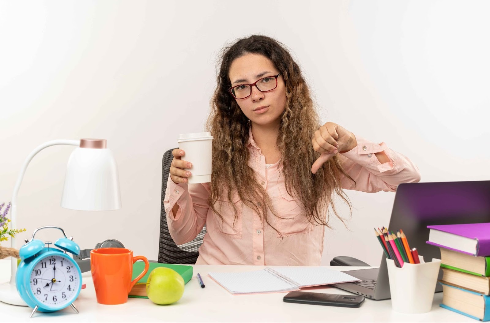 Woman giving a thumbs down next to a clock and coffee