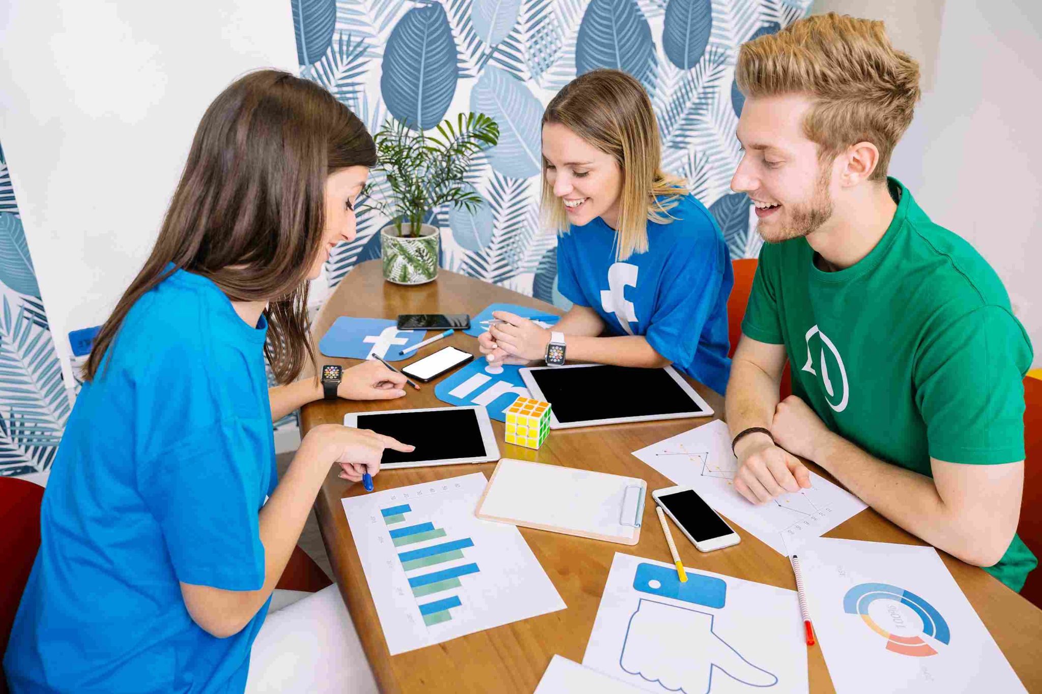 Three people looking at tablet and papers on a desk