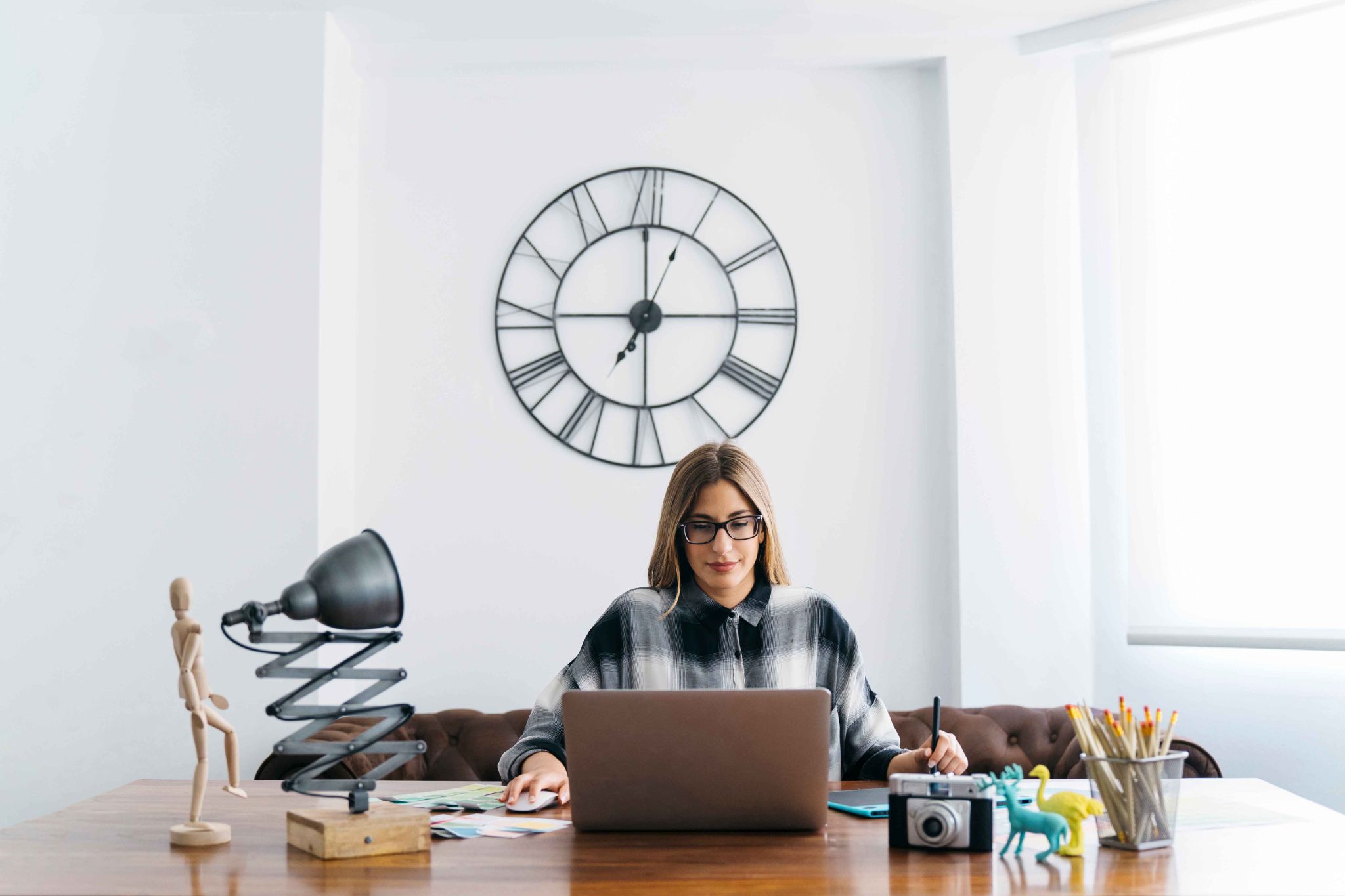 Remote worker using a laptop with a wall clock in the background