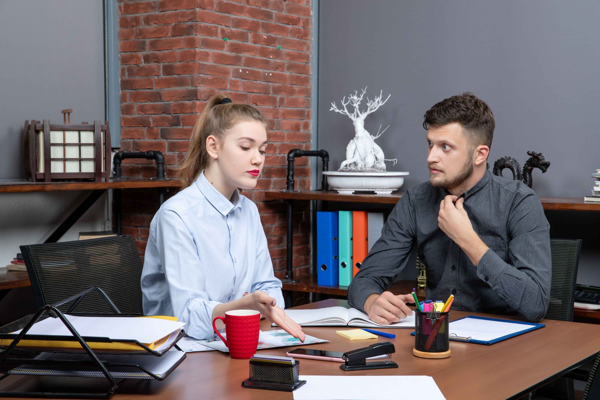 Two colleagues discussing work at a desk