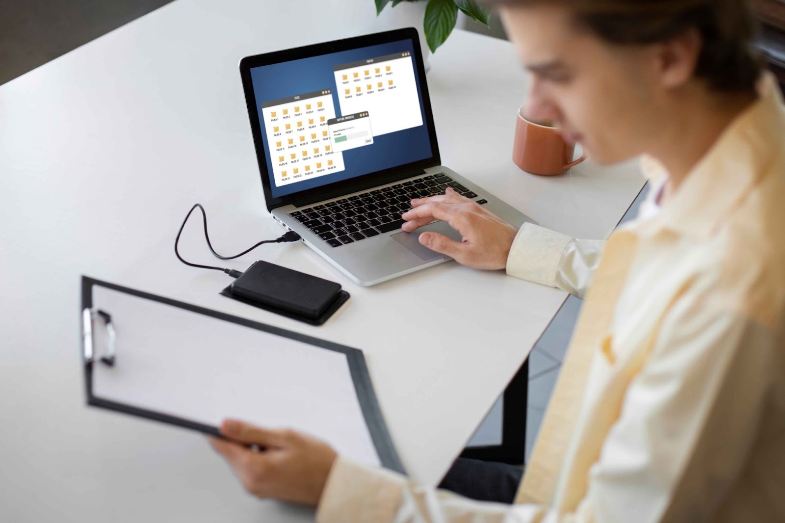 Person using a laptop and clipboard