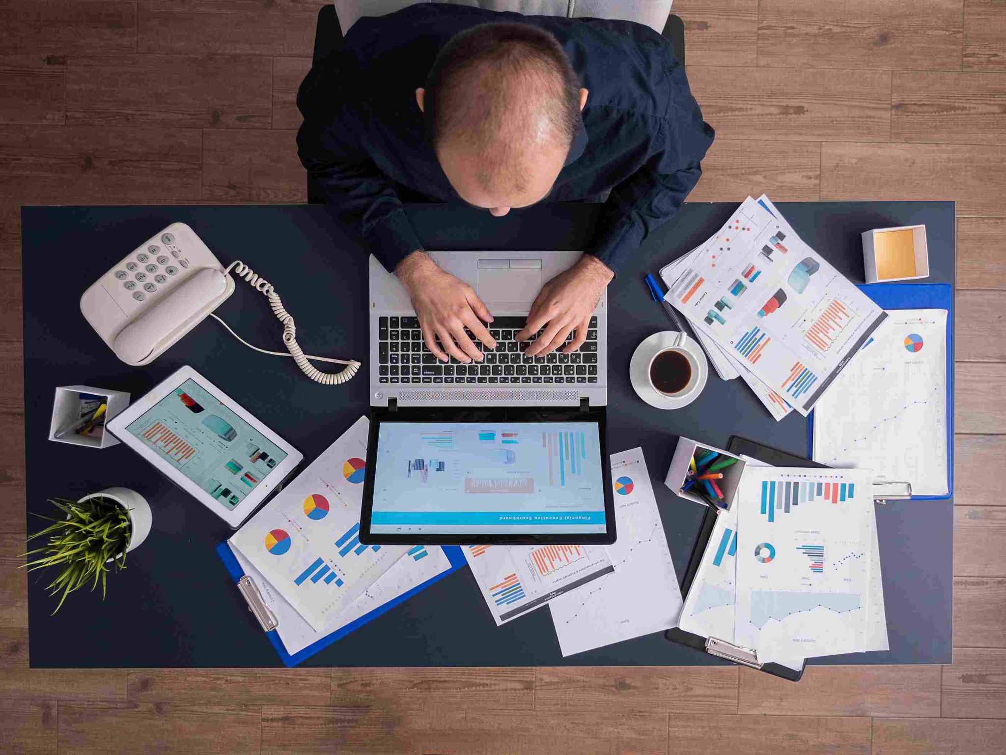 Overhead view of a person working at a desk with laptop and papers