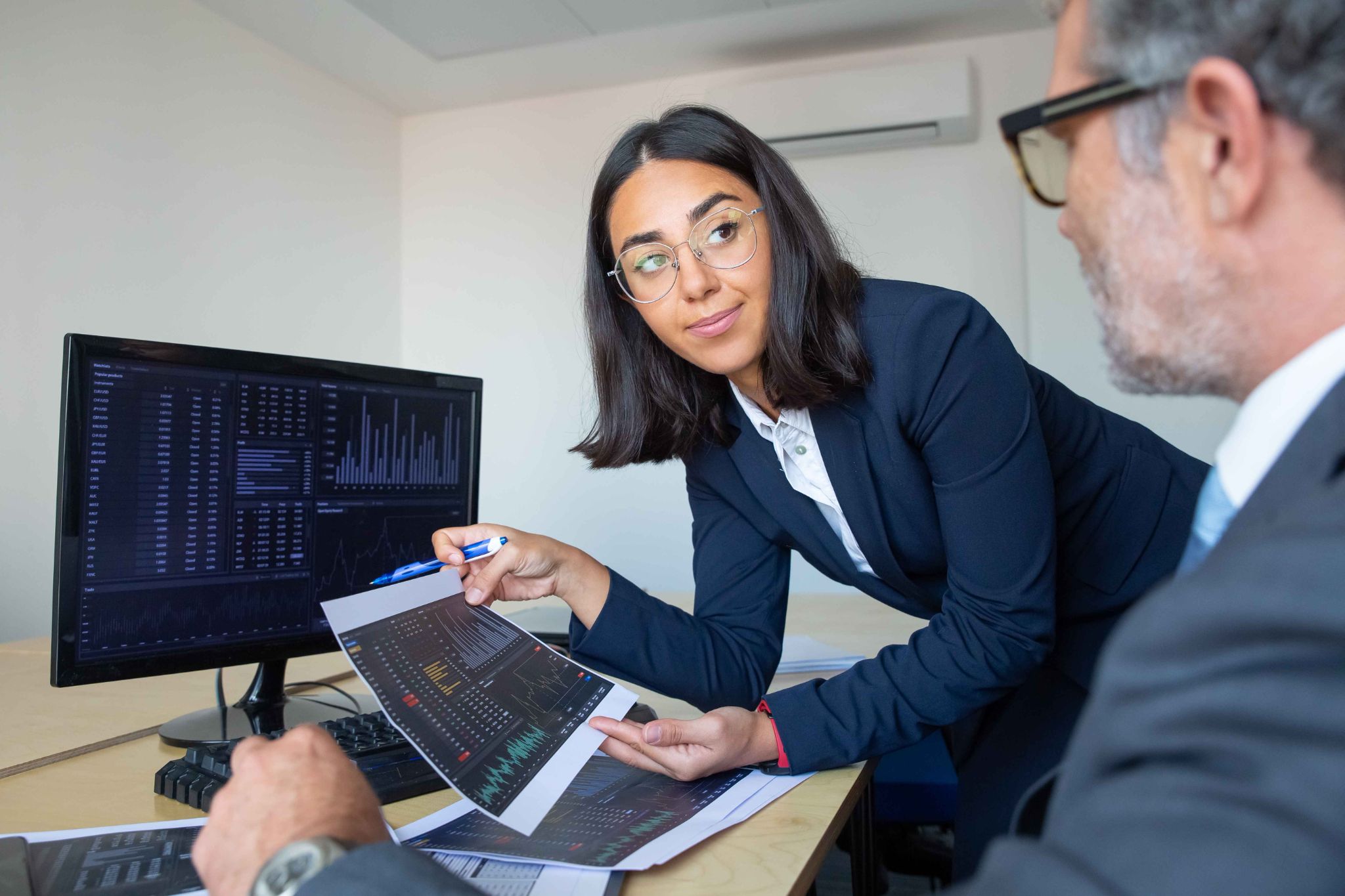Two professionals reviewing payroll data on a computer and paper reports